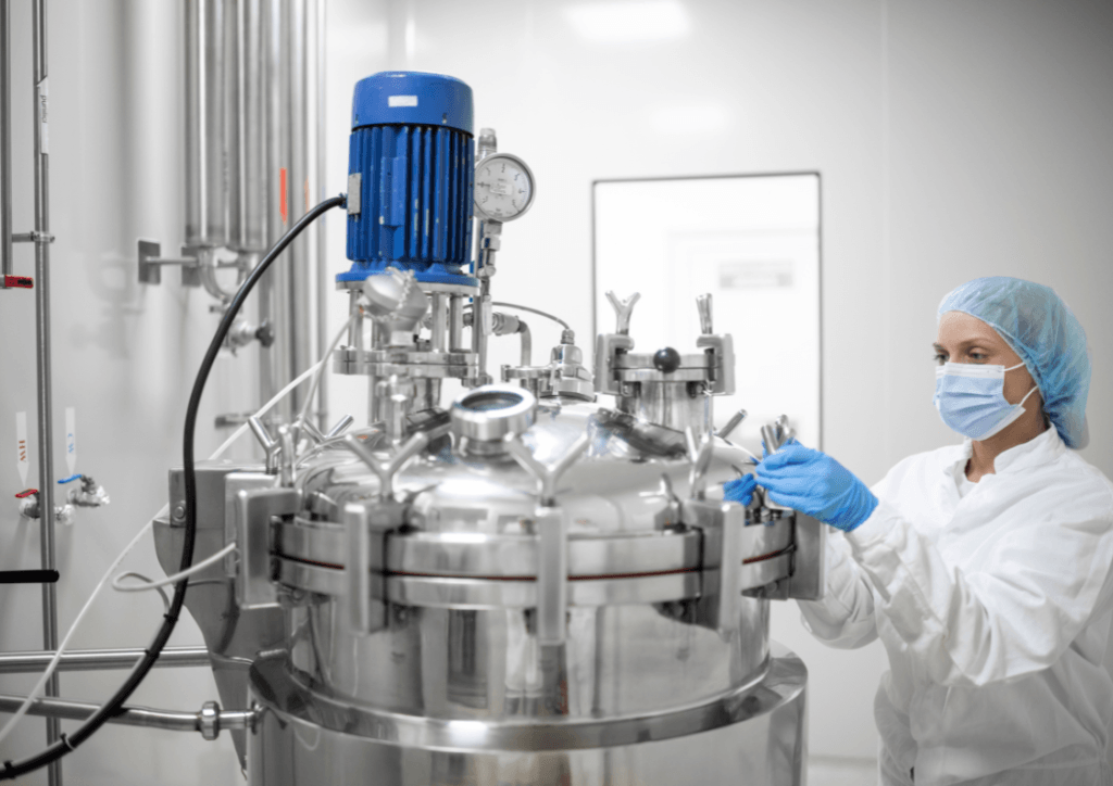 Technician operating a stainless steel bioreactor in a biopharma manufacturing clean room